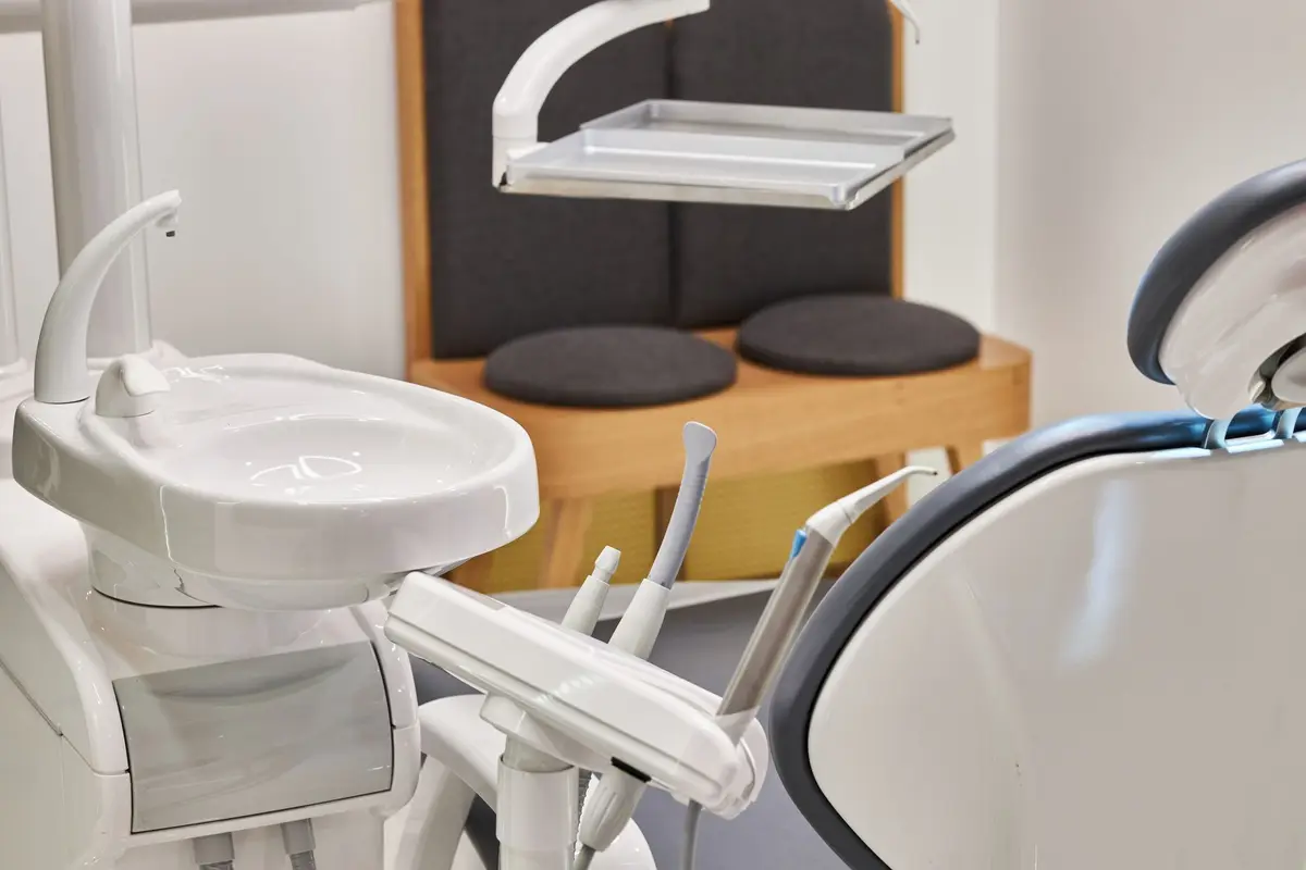 A dental chair and delivery unit in a bright operatory with seating by the window